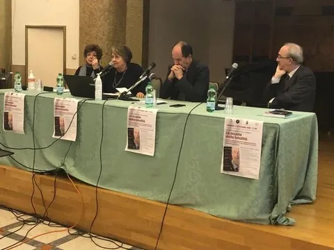 Il tavolo dei relatori con le locandine de La Scuola della Totalità